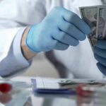 Gloved hands in a lab coat counting US dollar bills