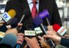 White House Locks Out Reporters Press microphones surround a suited spokesperson