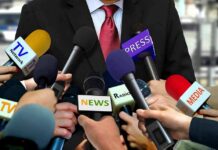 White House Locks Out Reporters Press microphones surround a suited spokesperson