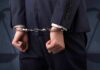 Businessperson in handcuffs with hands behind back