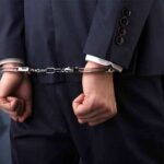 Businessperson in handcuffs with hands behind back
