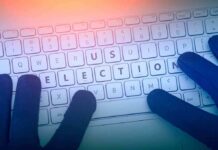 Gloved hands typing on a keyboard with highlighted election keys