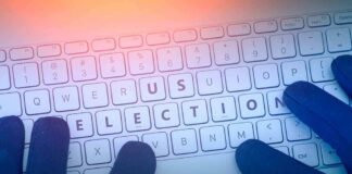 Gloved hands typing on a keyboard with highlighted election keys