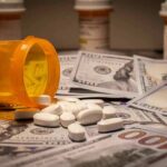 Prescription pill bottle and white tablets on scattered US dollar bills