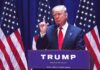 Energized Trump Stuns Prime-Time man in suit speaking at podium with multiple American flags