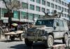 Armored military vehicle with mounted guns in busy city street