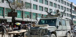 Armored military vehicle with mounted guns in busy city street