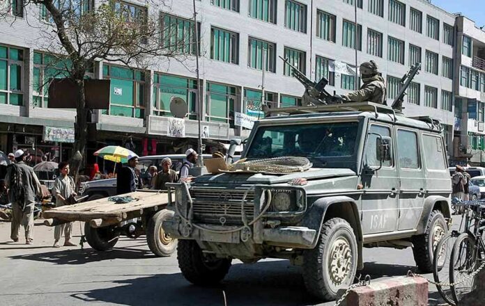 shutterstock_1476104171 Armored military vehicle with mounted guns in busy city street