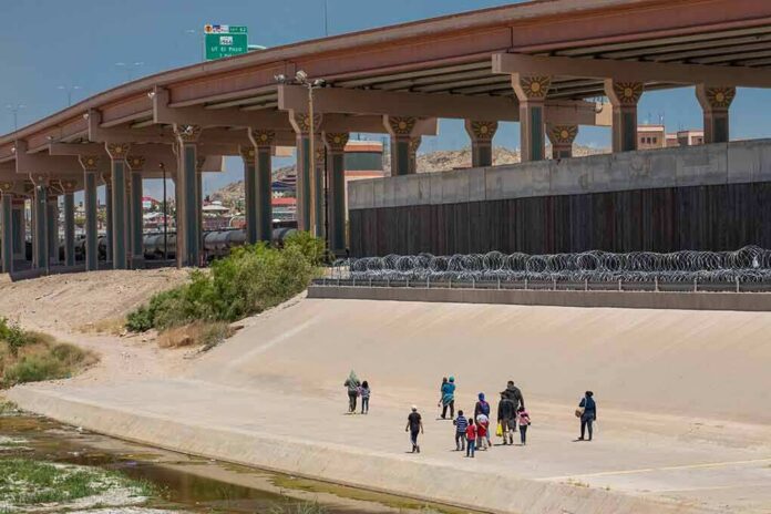 shutterstock_1483649366 Group of people walking in a concrete drainage channel near a highway overpass