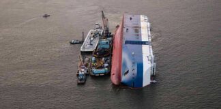 Capsized cargo ship with salvage vessels alongside
