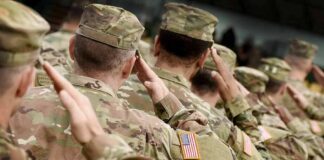 Soldiers in camouflage uniforms saluting