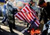 people burning a U.S. flag on a city street