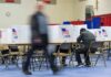 Voter fills out ballot at polling station with privacy booths