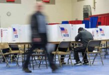 Washington Tightens The Ballot Voter fills out ballot at polling station with privacy booths