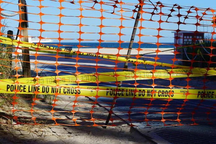 Orange safety net and yellow police tape blocking a beach access