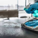 Explosive Diarrhea Wave Baffles Michigan Gloved hands spraying and wiping a tabletop