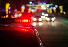 Drunk Dash Ends In Shocking Swamp Drop Police car with flashing red lights on a city street at night