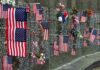 Memorial wall adorned with American flags and flowers