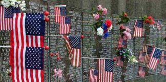 Memorial wall adorned with American flags and flowers