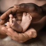 Adult hands cradling a newborn's feet