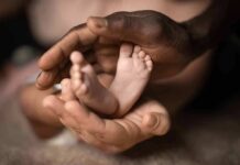 Adult hands cradling a newborn's feet