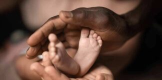 Adult hands cradling a newborn's feet