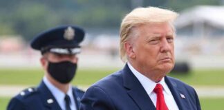 Donald Trump walking outdoors with an officer behind him; Chuck Howley not visible