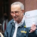 Senate Democrats Escalate Trump Battle man in FEMA jacket holding a printed tweet