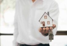 Hand holding a small house model and house-shaped key