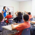 Communism Blast Hijacks High School Teacher leading classroom discussion with students raising hands
