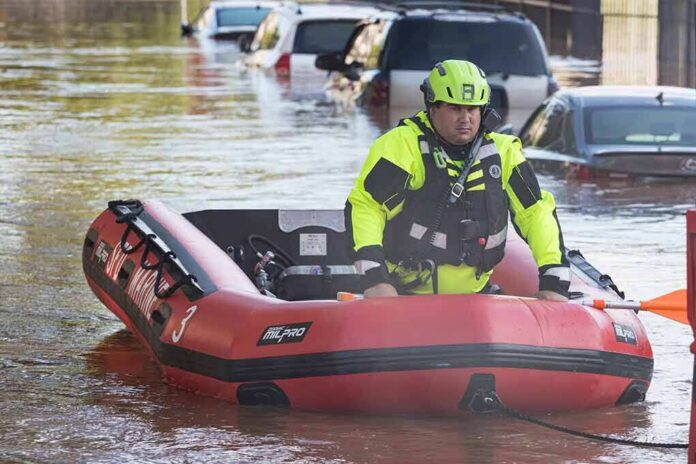 shutterstock_2035377782 Rescue worker in an inflatable boat during urban flooding