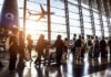 Passengers queue inside an airport terminal at sunset