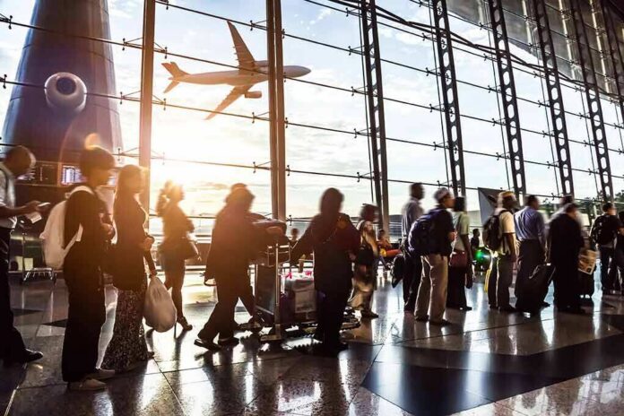 shutterstock_210042967 Passengers queue inside an airport terminal at sunset