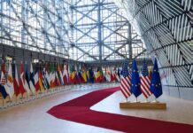 EU – Canada Power Play Tests Tariff Nerves Row of national flags in a modern glass atrium with red carpet and EU and US flags upfront