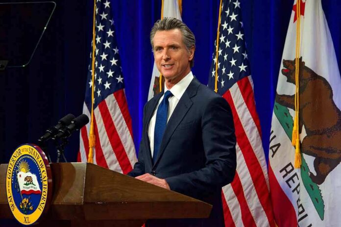 shutterstock_2137542759 Man in suit speaking at a podium with American and California flags