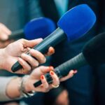 Will Fetterman Really Switch Parties? Reporters holding colorful microphones