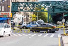 Queens Street Clash Ends In Blood Police cars block a city intersection with yellow crime scene tape