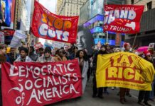 DSA Surge Rattles 2026 Primaries Protesters holding large banners at a city street demonstration