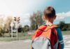 child with backpack waiting at crosswalk