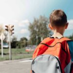 child with backpack waiting at crosswalk
