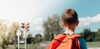 child with backpack waiting at crosswalk