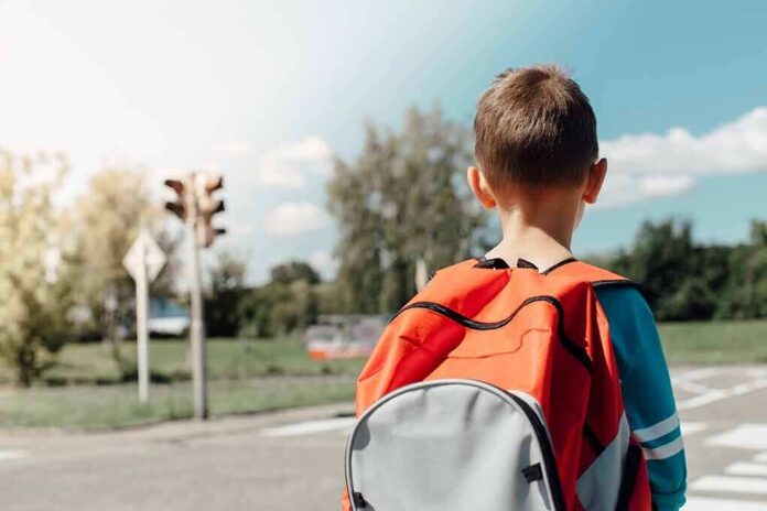 child with backpack waiting at crosswalk