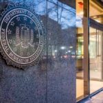 FBI emblem on a stone wall beside a glass entrance
