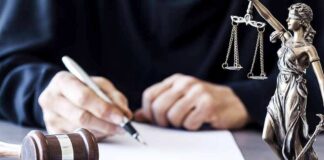 Judge writing at desk with gavel and Lady Justice statue