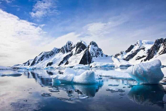 Icebergs floating before snow-covered mountains under a bright sky