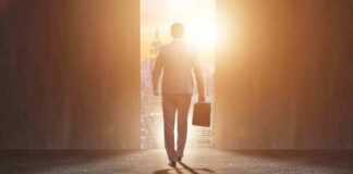 Businessman walking toward bright city doorway with briefcase