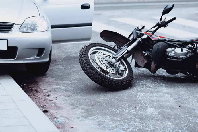 shutterstock_1032179767 Motorcycle lying on the street beside a car with an open door