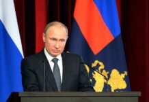 Vladimir Putin speaking at a podium with microphones