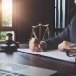 Lawyer writing at desk with gavel and scales