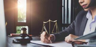 Lawyer writing at desk with gavel and scales